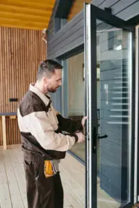 Young Repairman Standing Front Glass Door While Repairing Lock (1)